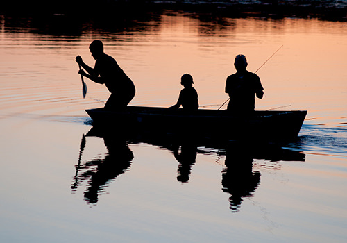 Photo a three people fishing inside a boat at dusk.